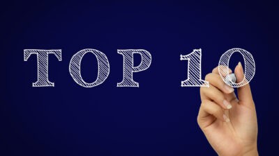 A woman's hand draws a stylised 'Top Ten' on a projected surface.'s hand draws a stylised 'Top Ten' on a projected surface.