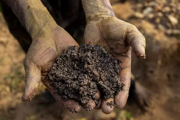 A miner shows a handful of earth and rock containing cassiterite and coltan, in Manono, DRC, on May 20, 2025.